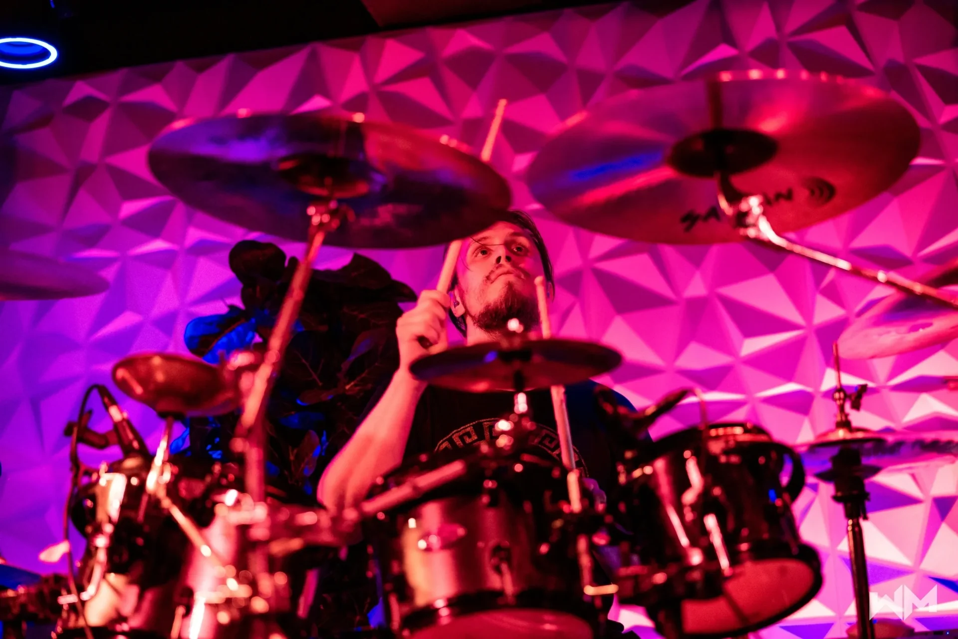 A person playing drums in front of a purple wall.