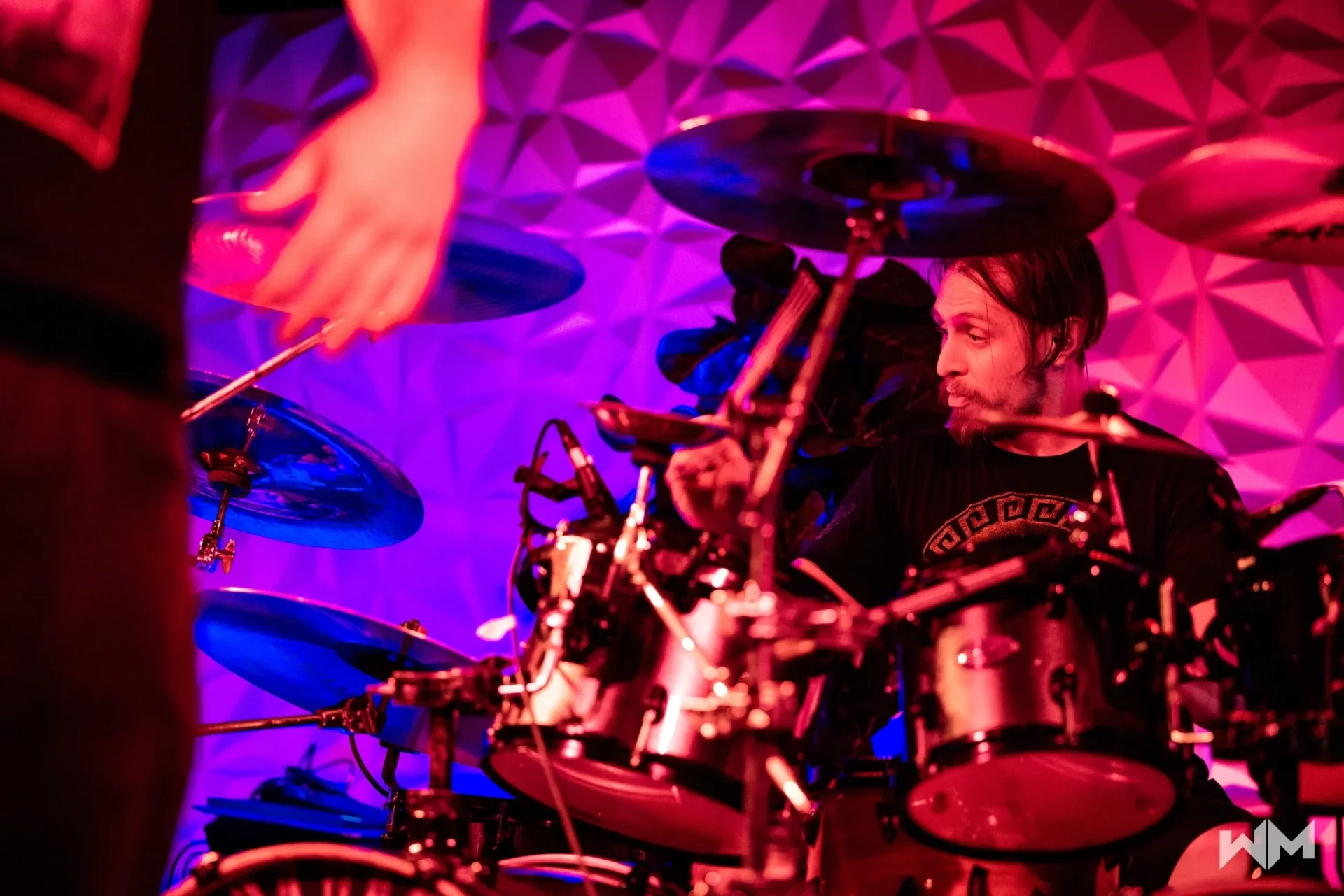 A man playing drums in front of purple lights.